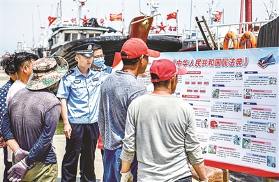 民法典表決通過(guò)后，各地結(jié)合實(shí)際開(kāi)展多種形式的普法宣傳。圖為山東省東營(yíng)市民警和社區(qū)網(wǎng)格員在漁港碼頭為漁民宣講民法典內(nèi)容。（圖片來(lái)源：視覺(jué)中國(guó)）